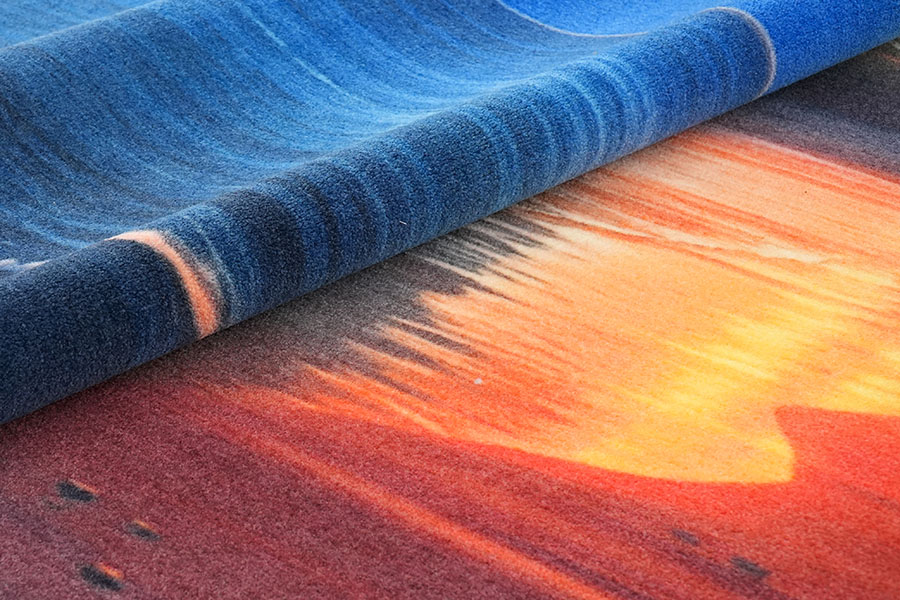 Ein lebendiger, maßgefertigter Nylon-Teppich mit Sonnenuntergang-Design, bei dem blaue, orange, rote und gelbe Farben ineinander übergehen und die Kurzflor-Details zur Geltung kommen.